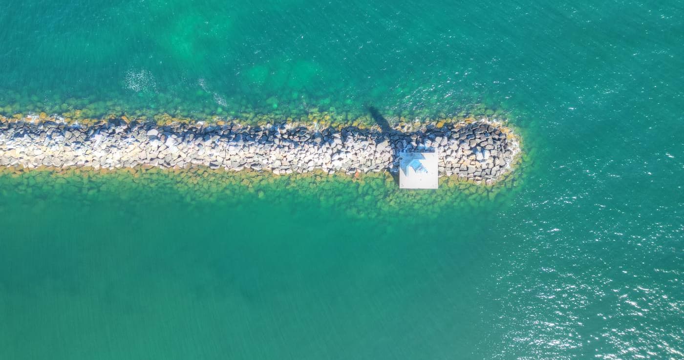 Overhead view of a rubble breakwater reaching into the clear emerald water of Lake Superior.